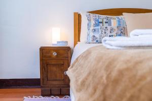 una camera da letto con un letto e un comodino con una lampada di Sleep Among the Bananas! Rustic Cottage with Trails at Your Doorstep a Ponta do Sol