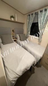 2 Betten in einem Schlafzimmer mit weißer Bettwäsche in der Unterkunft AJH Holiday Homes, Ty Mawr- Parkdeans Resort in Kinmel Bay