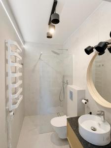 een badkamer met een toilet, een wastafel en een spiegel bij OWysoko - Apartamenty z Widokiem 200 m od tras Szczyrk Mountain Resort in Szczyrk