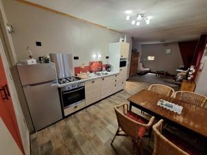 a kitchen with a refrigerator and a table with chairs at Gîte De La Souris Verte in Molamboz