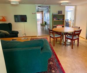 a living room with a green couch and a table at Mössebergs vandrarhem in Falköping