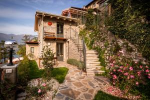 una casa de piedra con escaleras y flores en una colina en Le Casette Apartments - byMyHomeinComo, en Blevio