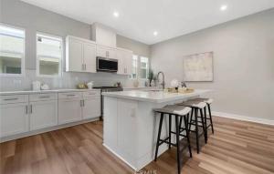 a kitchen with white cabinets and bar stools at 1311WCara in Anaheim