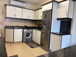 una cocina con nevera y lavadora en Tenbury Beach Apartment 208, en Durban