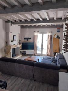 salon z dużą kanapą i gitarą w obiekcie Maison de vacances 3 chambres avec terrasses w mieście Saint-Georges-de-Didonne
