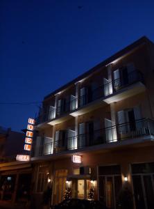 納夫普利翁的住宿－赫拉酒店，夜间带有 ⁇ 虹灯标志的酒店大楼