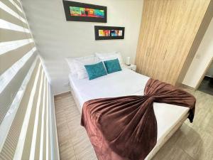 Un dormitorio con una cama blanca con almohadas azules. en M510- Apartaestudio en Av19 Norte con parqueadero, en Armenia