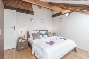 a white bedroom with two beds and a brick wall at Hybernska Apartments in Prague