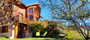 a house with a balcony and a table and chairs at Chalet Bon Accueil in Briançon