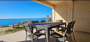 a table and chairs on a patio with the ocean at T3 Paradisiaque sur la plage, les pieds dans l'eau in Olmeto