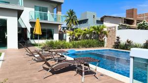 a patio with tables and chairs next to a swimming pool at Barra de Jacuípe - Condomínio Parque Jacuípe -Mansão Caldeira in Camaçari