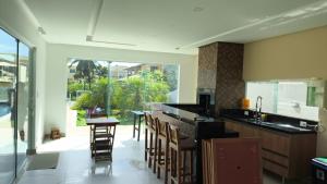 a kitchen with a bar with chairs and a table at Barra de Jacuípe - Condomínio Parque Jacuípe -Mansão Caldeira in Camaçari