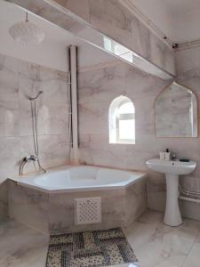 a white bathroom with a tub and a sink at Maison RKA in Bejaïa
