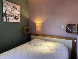 a bedroom with a bed and a lamp on the wall at Résidence Le Pédrou - maeva Home - Appartement 2 pièces 4 personnes - Sélection MAE-8531 in Font Romeu Odeillo Via