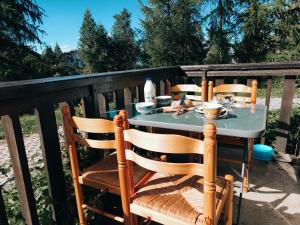 a table with chairs on a balcony with a meal on it at Appart Cosy 4 Personnes - Ski aux Pieds, Les Orres in Les Orres