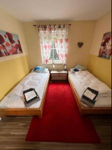 two beds in a room with a red carpet at FeWo Sonnenblick - Meer Urlaub in Fehmarn