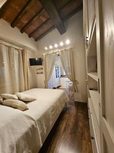 a bedroom with a large white bed and wooden floors at Piccolo Cottage Country Oasi di Pace in Collesalvetti