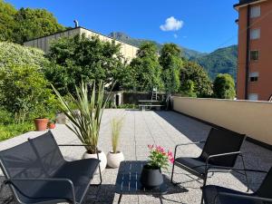 a patio with chairs and potted plants on a building at Sweet Menaggio in Menaggio