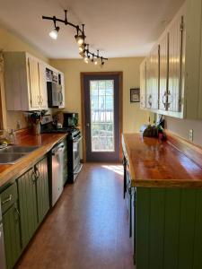 a kitchen with green cabinets and a wooden counter top at Hawkeyes Rest in Johnsburg
