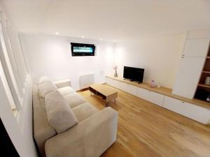 a white living room with a couch and a tv at L'underground - parking - jardin in Huningue