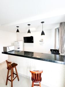 a kitchen with a black counter and two chairs at Morada DaLuz in Barra Grande