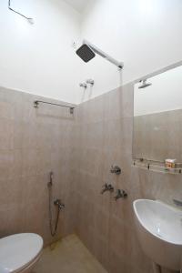 a bathroom with a sink and a toilet and a mirror at Bonobitaan Hotel & Restaurant in Srī Niketan
