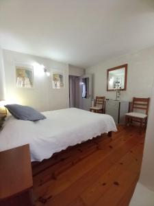a bedroom with a large white bed and two chairs at Casa do Paço com Jardim Privado - Centro de Terras de Bouro, Gerês in Terras de Bouro