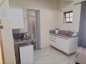 a kitchen with white cabinets and granite counter tops at Kitnets Dona Lucia SJC in São José dos Campos