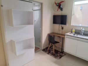 a kitchen with a shower and a desk and a chair at Kitnets Dona Lucia SJC in São José dos Campos