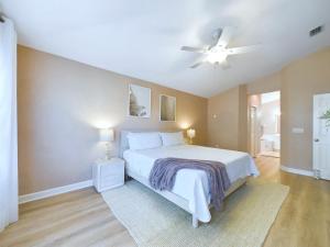 a bedroom with a white bed and a ceiling fan at Coastal Bliss Retreat - Beach Vibes & Rockets in Cocoa Beach
