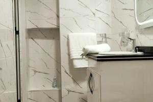 a bathroom with white marble walls and a shower at Corniche House in Nador