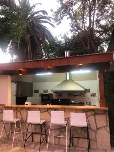 a bar with four pink chairs in front of a kitchen at Like at Home Ezeiza in Ezeiza
