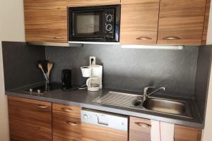 a kitchen with a sink and a microwave at Charmant T2 au cœur du village in Hauteluce +5 photos
