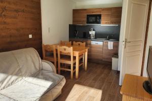 a living room with a table and a kitchen at Charmant T2 au cœur du village in Hauteluce