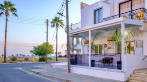 a white building with palm trees on the street at FatCow Beach Apartment in Larnaka