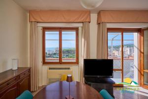 a living room with a table and a tv and two windows at Maremma Holidays Zot's Penthouse in Follonica