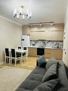 ein Wohnzimmer mit einem Sofa und eine Küche mit einem Tisch in der Unterkunft Двухкомнатная квартира in Taldykolʼ