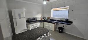a small kitchen with a sink and a refrigerator at Casa, Piscina, Sinuca Churrasqueira, Ping Pong, Praia Guarujá in Guarujá