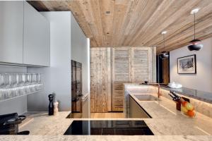 Una cocina con fregadero y techo de madera. en Antarès MIRA 102 - luxury apartment ski inski out, en Méribel