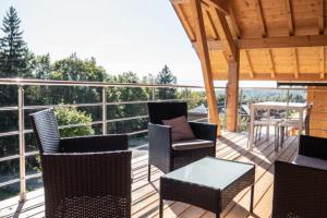 a deck with chairs and a table and a view of trees at Chalet Cozy au Cœur de La Féclaz Séjour Authentique et Proche des Pistes in La Féclaz