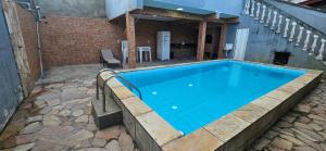 a swimming pool with blue water in a building at Casa, Piscina, Sinuca Churrasqueira, Ping Pong, Praia Guarujá in Guarujá