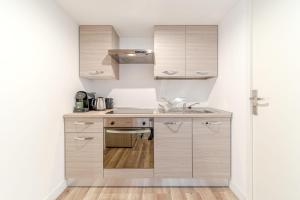Una cocina con gabinetes blancos y un fregadero. en Maison Fontanières Studio Navarre 1 person, en La Mulatière