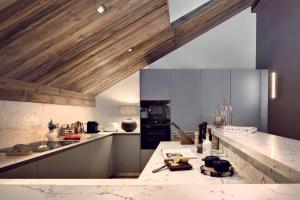 eine Küche mit weißen Theken und Holzdecken in der Unterkunft Antarès NAOS 501D - somptuous duplex penthouse luxury ski inski out in Méribel