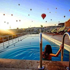 ギョレメにあるDoors Of Cappadocia Special Cave Hotelの熱気球のプールに立つ女