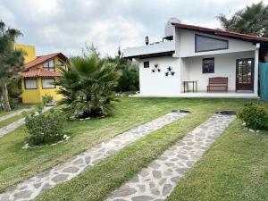 a house with a stone walkway in front of a yard at Cabañas Ojo de Agua in Mazamitla