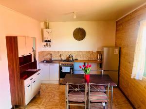 a kitchen with a table and chairs and a refrigerator at Cabañas Piedra de Condores in Bahía Murta