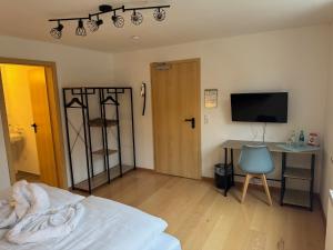 a bedroom with a bed and a desk and a television at Deutsche Eiche Hotel & Restaurant in Grebenstein