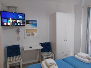 a room with two beds and a tv on the wall at Villa Rosanna in Plataria