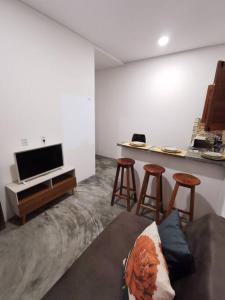 Sala de estar con sofá, mesa y taburetes en Rancho do Poeta - Chalé Umbucajá, en Lagoa Nova