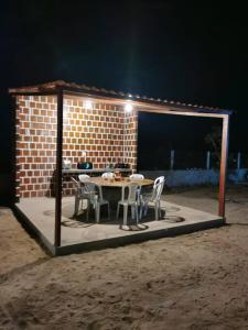 Un patio con una mesa y sillas y una pared de ladrillos. en Rancho do Poeta - Chalé Umbucajá, en Lagoa Nova